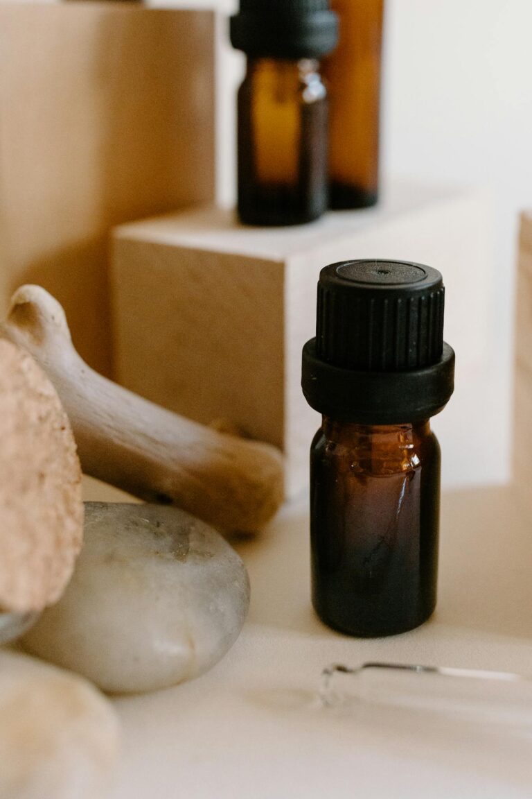 Essential oil bottle surrounded by natural stones and wooden blocks, perfect for aromatherapy concepts.